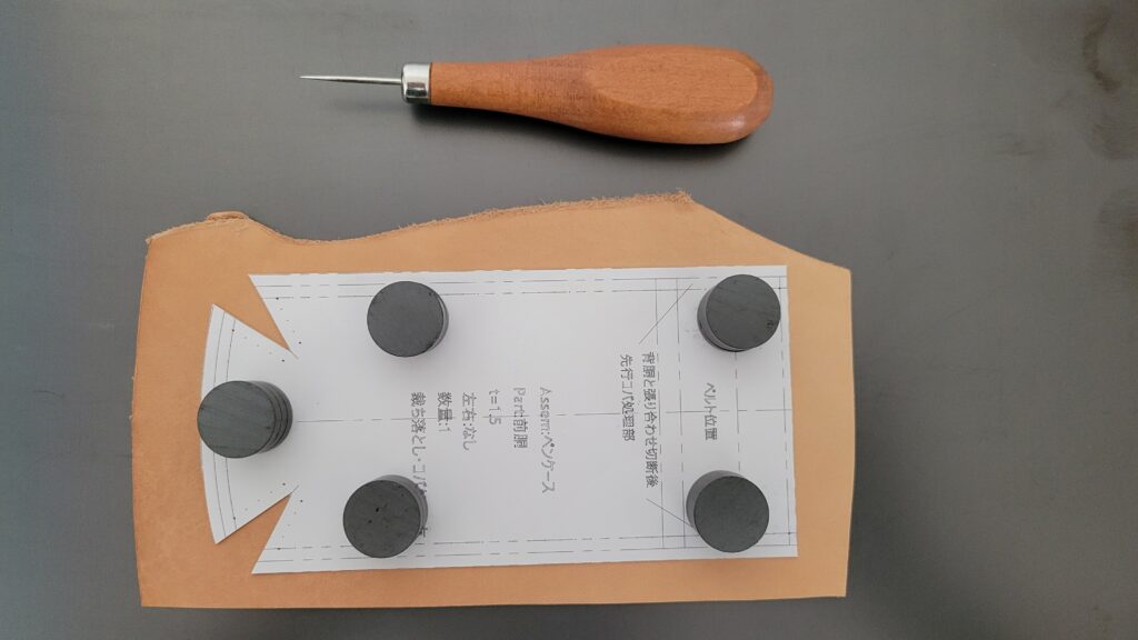 マグネットで型紙を革に仮留めしている様子